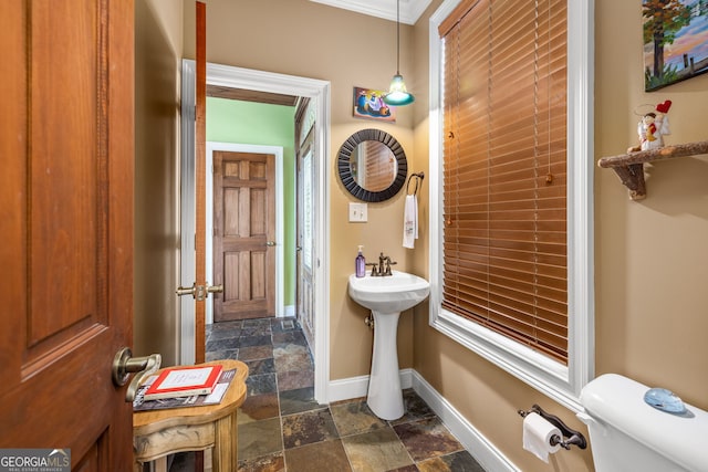 bathroom featuring toilet, baseboards, and stone tile flooring