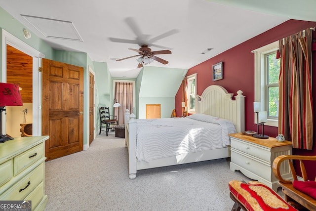 bedroom with ceiling fan, visible vents, vaulted ceiling, and attic access