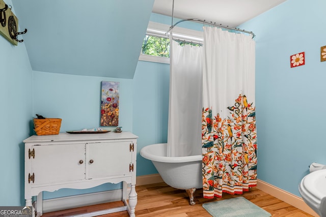 full bath featuring a shower with curtain, a freestanding tub, wood finished floors, and baseboards