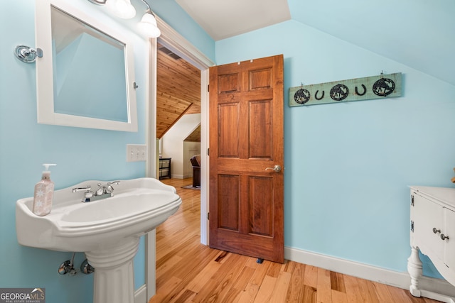 bathroom with baseboards, vaulted ceiling, and wood finished floors