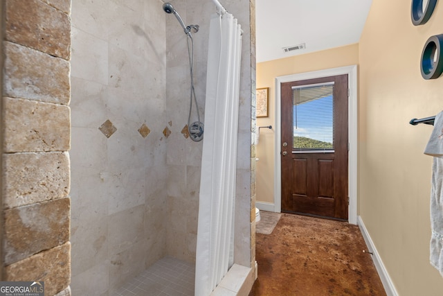 full bathroom featuring visible vents, baseboards, and tiled shower