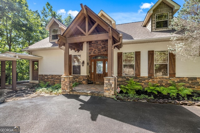 view of front of property featuring stone siding, roof with shingles, and stucco siding