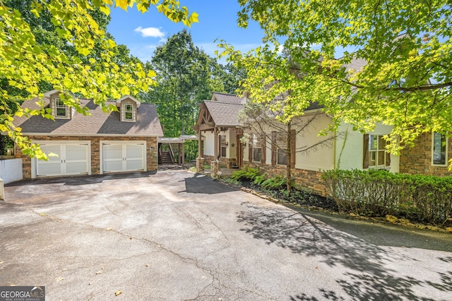 view of front of property featuring a garage, stone siding, and a shingled roof