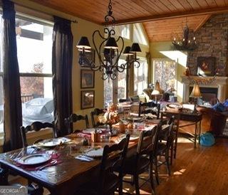 dining area featuring vaulted ceiling with beams, wooden ceiling, a fireplace, and wood finished floors