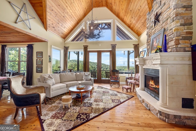 living room featuring a wealth of natural light, a stone fireplace, hardwood / wood-style flooring, and a notable chandelier