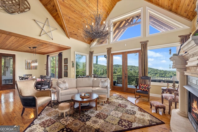 living room with wooden ceiling, a warm lit fireplace, a chandelier, and hardwood / wood-style flooring