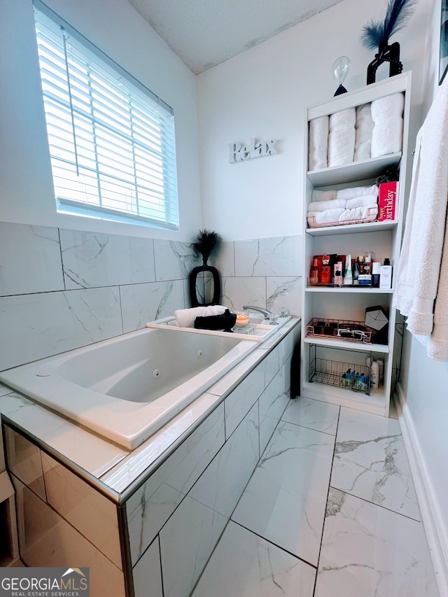 interior space featuring marble finish floor, baseboards, and a whirlpool tub