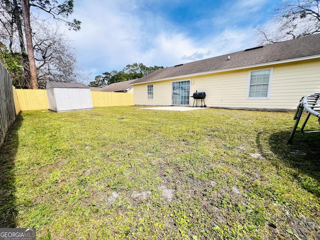 view of yard with an outbuilding, a storage unit, a patio area, and a fenced backyard