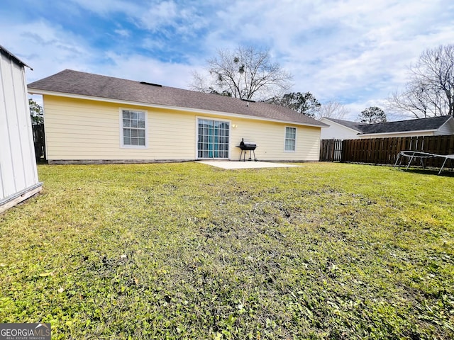 rear view of property featuring a patio, a lawn, and fence