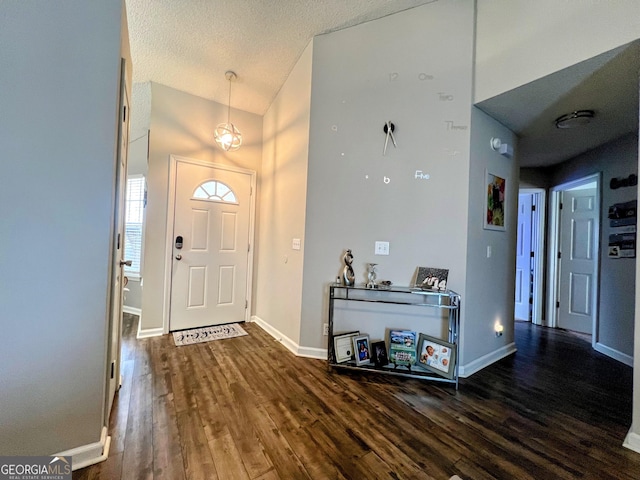 entryway with a textured ceiling, baseboards, and wood finished floors