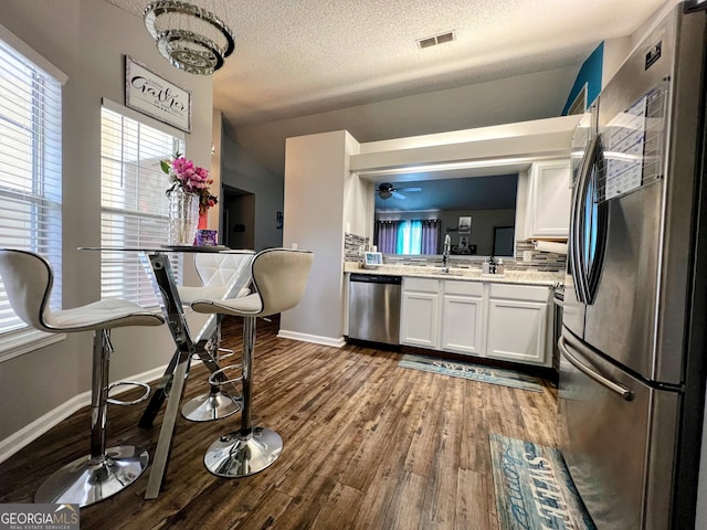 kitchen featuring stainless steel appliances, dark wood-type flooring, visible vents, white cabinets, and light countertops