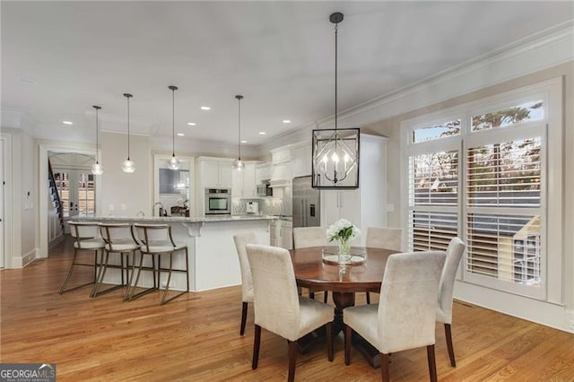 dining area with light wood-type flooring, a wealth of natural light, and crown molding