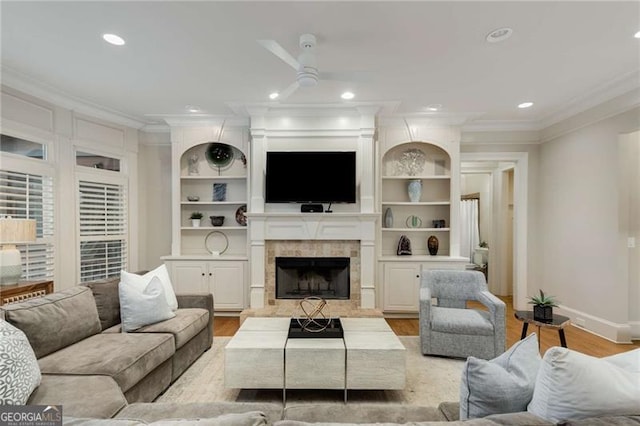 living area featuring ornamental molding, light wood-type flooring, a fireplace, and recessed lighting