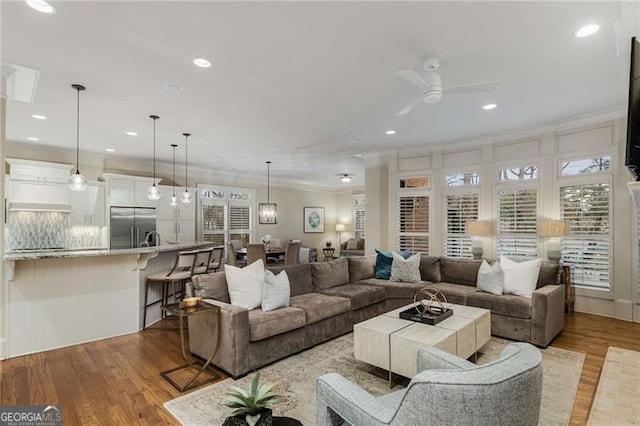 living room with light wood-style flooring, ornamental molding, a ceiling fan, and recessed lighting