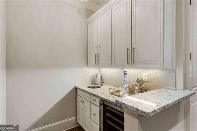 bar featuring baseboards, wine cooler, a sink, and decorative backsplash