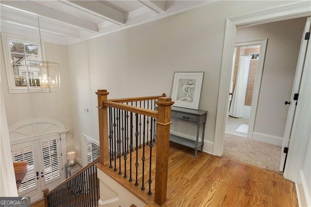 corridor with visible vents, wood finished floors, beamed ceiling, an inviting chandelier, and an upstairs landing