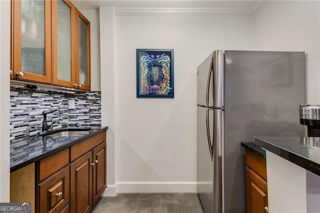 kitchen with tasteful backsplash, freestanding refrigerator, dark stone counters, and a sink