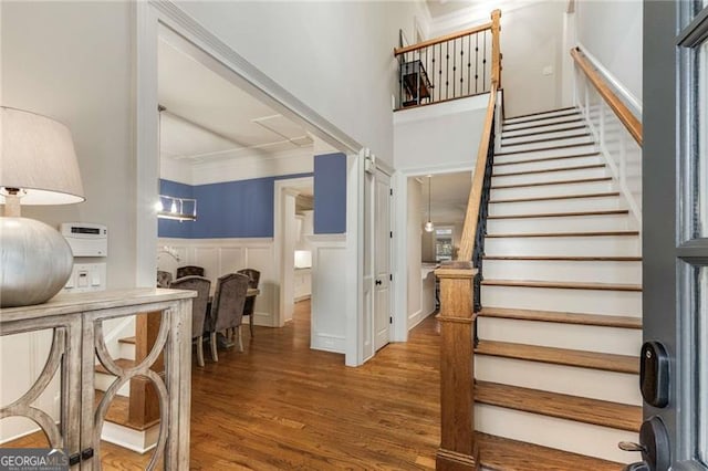 interior space with a wainscoted wall, stairway, ornamental molding, wood finished floors, and a decorative wall