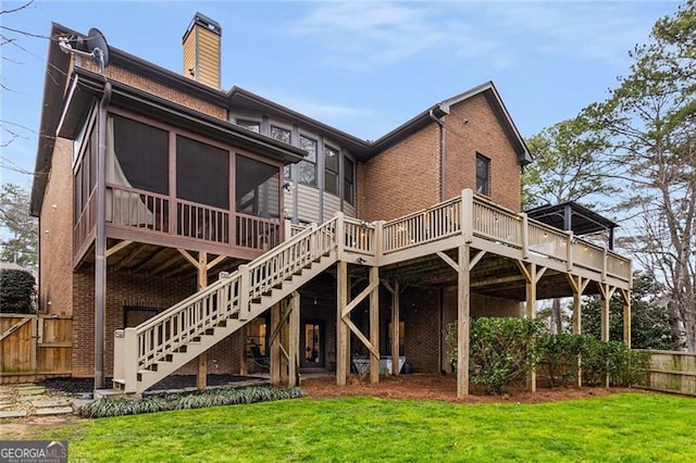 rear view of house with a lawn, stairs, fence, a deck, and brick siding