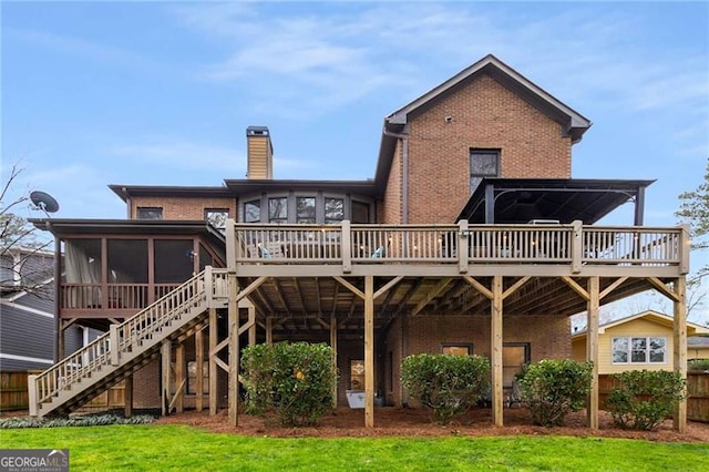 back of house with brick siding, a chimney, a sunroom, a wooden deck, and stairs