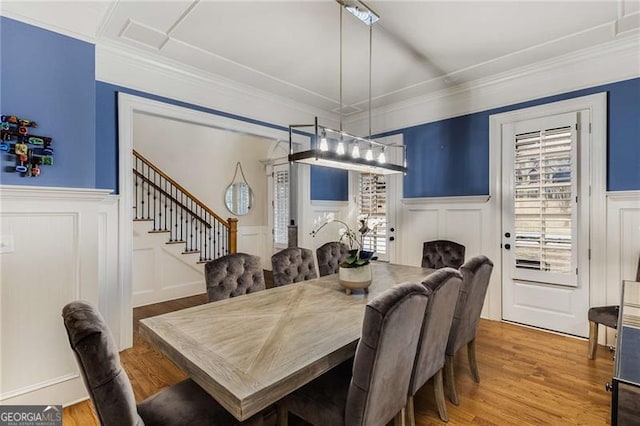 dining room with stairway, wainscoting, wood finished floors, and crown molding