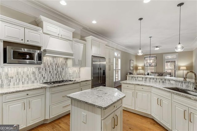 kitchen featuring stainless steel appliances, premium range hood, a sink, light wood-type flooring, and backsplash