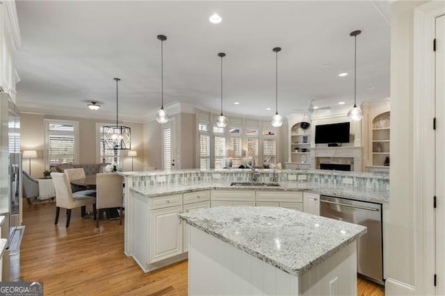 kitchen featuring dishwasher, open floor plan, a center island, crown molding, and a sink