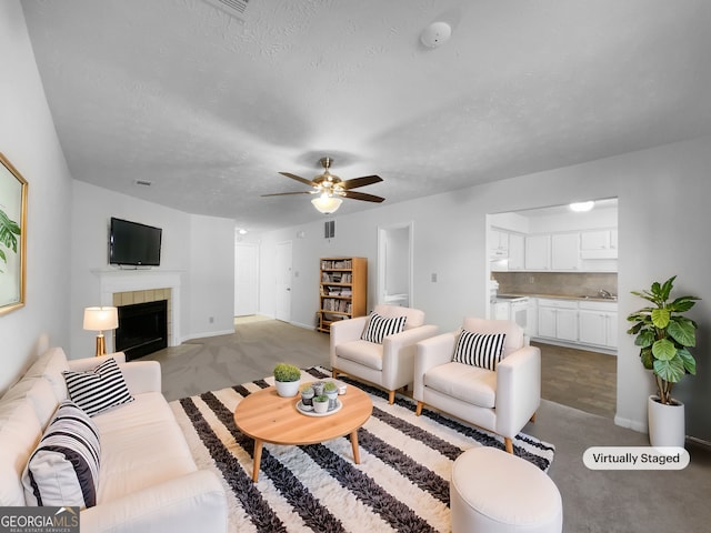 living room featuring visible vents, carpet flooring, ceiling fan, a textured ceiling, and a tile fireplace