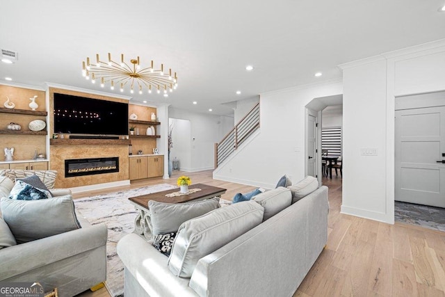 living room with a glass covered fireplace, ornamental molding, stairs, light wood-style floors, and recessed lighting