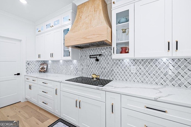 kitchen featuring black electric stovetop, custom exhaust hood, backsplash, ornamental molding, and white cabinets