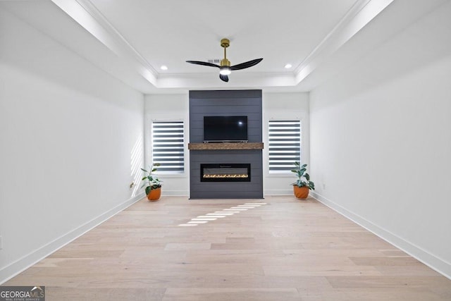 unfurnished living room with baseboards, a ceiling fan, ornamental molding, wood finished floors, and a tray ceiling