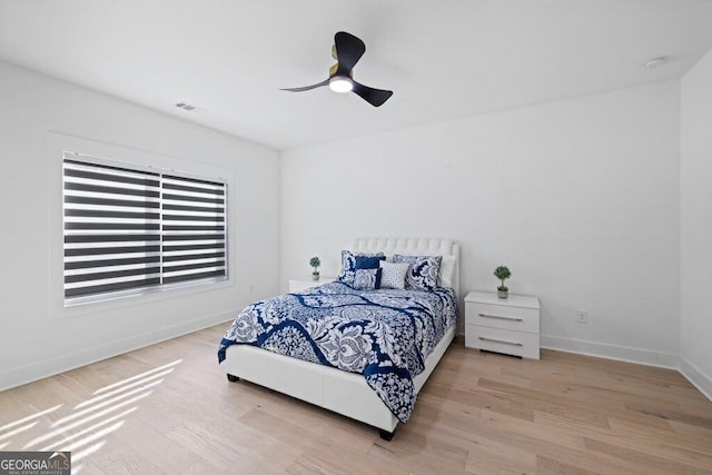 bedroom with a ceiling fan, wood finished floors, visible vents, and baseboards