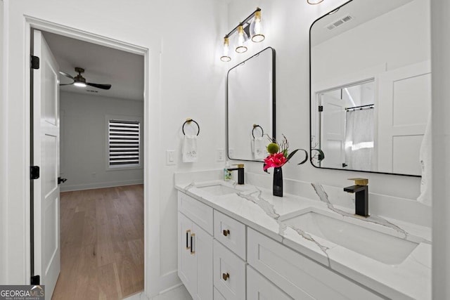 bathroom with double vanity, wood finished floors, a sink, and visible vents