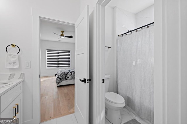 ensuite bathroom with curtained shower, toilet, vanity, a ceiling fan, and marble finish floor