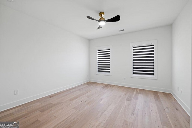 empty room with ceiling fan, light wood finished floors, and baseboards