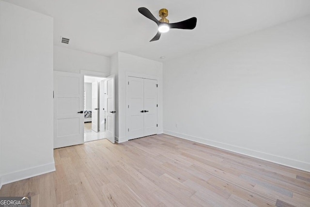 unfurnished bedroom with a closet, visible vents, light wood-style floors, ceiling fan, and baseboards