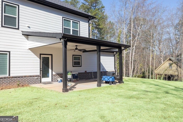 rear view of house with brick siding, a ceiling fan, roof with shingles, a lawn, and a patio area