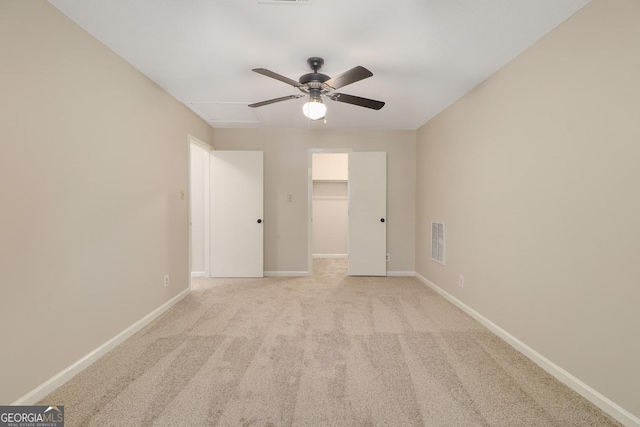 unfurnished bedroom featuring a walk in closet, visible vents, a ceiling fan, carpet flooring, and baseboards