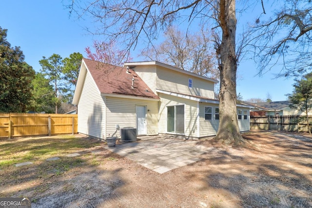 rear view of property with a fenced backyard, central AC unit, a shingled roof, and a patio