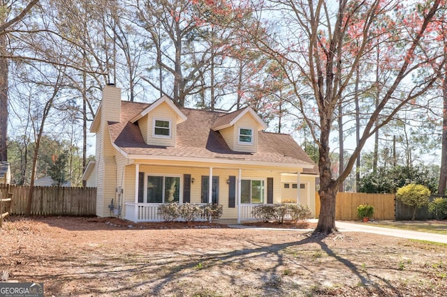 cape cod house with covered porch, a garage, a shingled roof, fence, and a chimney