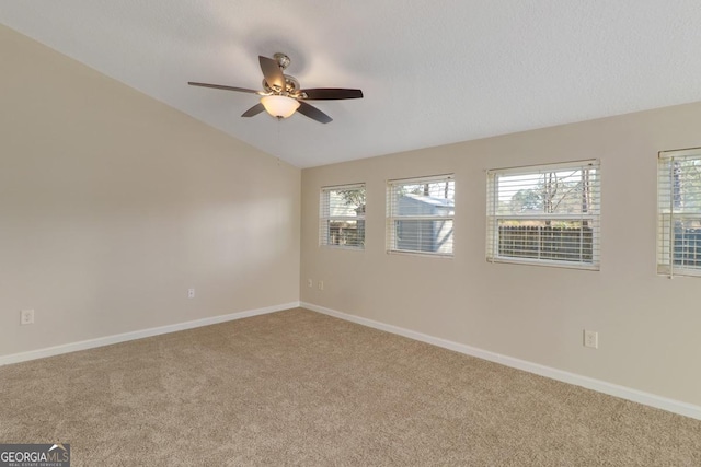 empty room with carpet floors, ceiling fan, baseboards, and lofted ceiling