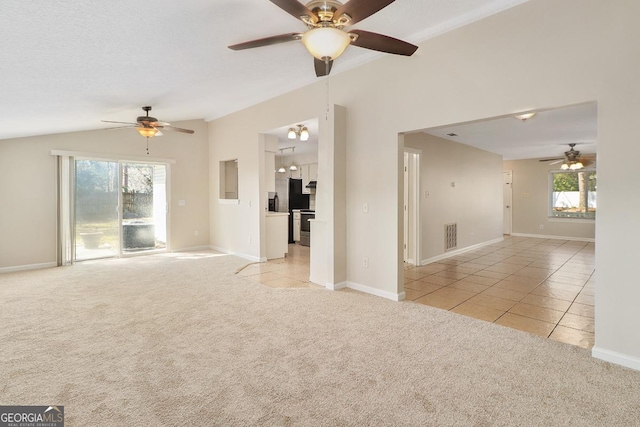 empty room with lofted ceiling, light colored carpet, a textured ceiling, and light tile patterned floors