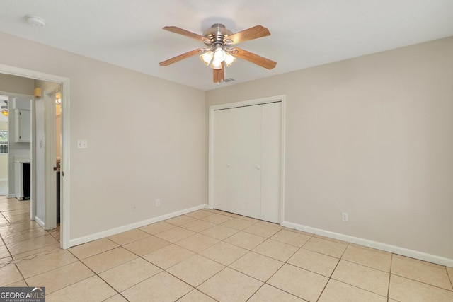 empty room featuring light tile patterned floors, ceiling fan, visible vents, and baseboards