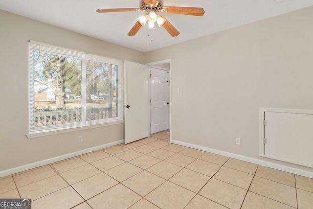 unfurnished room with ceiling fan, baseboards, and light tile patterned floors