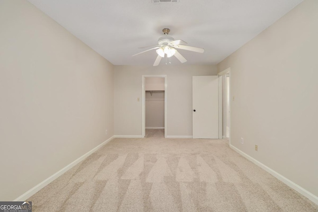 unfurnished bedroom featuring a closet, visible vents, light colored carpet, a spacious closet, and baseboards