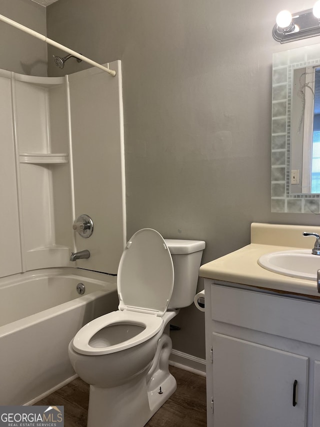 bathroom with toilet, wood finished floors, vanity, baseboards, and shower / bathing tub combination