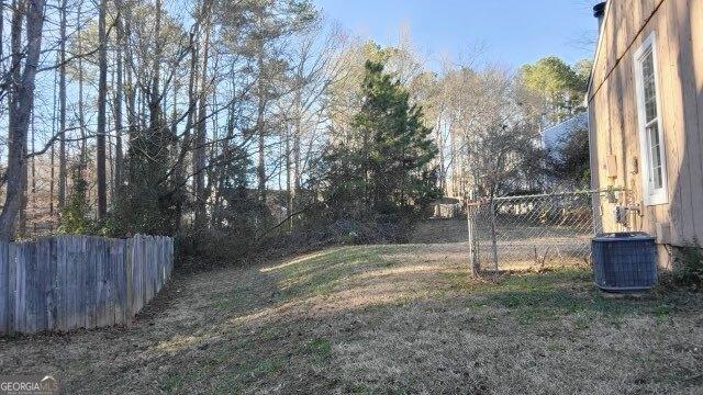 view of yard with fence and central AC unit