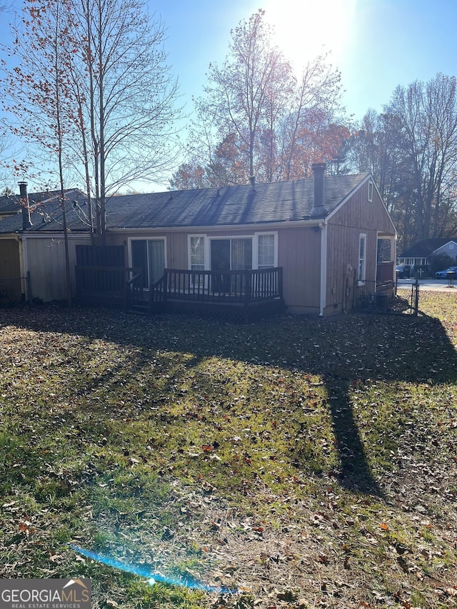 rear view of property featuring a chimney and a wooden deck