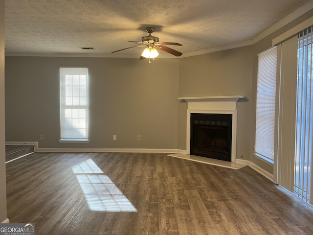 unfurnished living room featuring visible vents, a fireplace with raised hearth, dark wood-style flooring, and ornamental molding