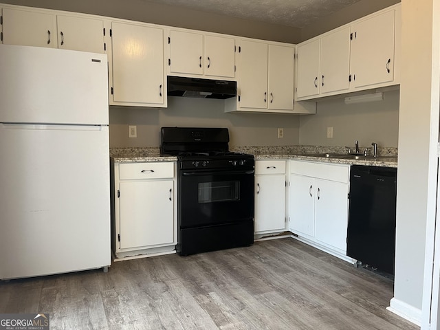 kitchen with under cabinet range hood, a sink, white cabinetry, light wood-type flooring, and black appliances